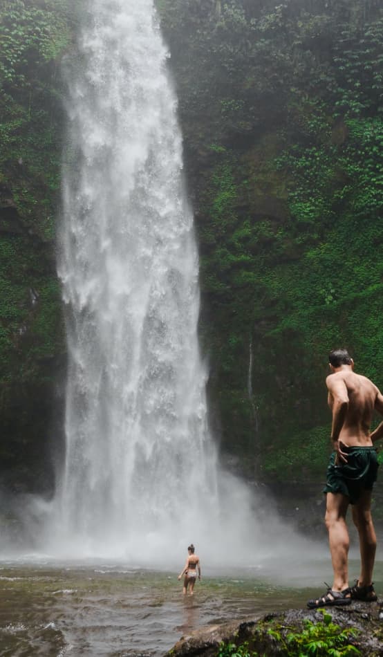 A couple bathe in a waterfall